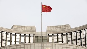 A Chinese flag flies in front of the People's Bank of China headquarters in Beijing, China, on Monday, Jan. 7, 2019. The central bank on Friday announced another cut to the amount of cash lenders must hold as reserves in a move to release a net 800 billio