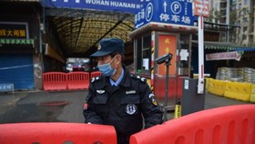 Trong một hình ảnh vào ngày 24 tháng 1, một sĩ quan cảnh sát đứng canh gác bên ngoài chợ bán buôn hải sản Huanan, nơi một số báo cáo cho rằng đại dịch bắt đầu. (Ảnh: © HECTOR RETAMAL / AFP qua Getty Images)
