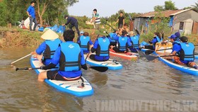 Dùng ván chèo vớt rác và tuyên truyền bảo vệ môi trường