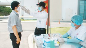 Người bệnh và người nhà bệnh nhân được đo thân nhiệt, khai báo y tế ngay từ cổng bệnh viện Ảnh: MINH NAM