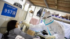 Nhân viên y tế kiểm tra thân nhiệt một bệnh nhân nghi nhiễm COVID-19. (Ảnh: AFP/TTXVN)