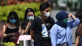 Người dân đeo khẩu trang phòng dịch viêm đường hô hấp cấp do virus COVID-19 tại Singapore. (Ảnh: AFP/TTXVN)