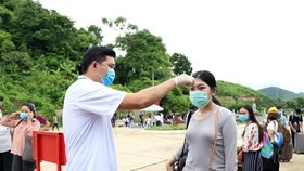 Lực lượng chức năng kiểm tra thân nhiệt lưu học sinh Lào tại cửa khẩu Chiềng Khương, tỉnh Sơn La. (Ảnh: Hữu Quyết/TTXVN)