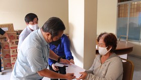 Phó Bí thư Thường trực Huyện ủy Hóc Môn Nguyễn Anh Tuấn trao tiền hỗ trợ cho người bán vé số lưu động. Ảnh: QUỲNH THY