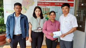 Ông Nguyễn Hữu Quế (bên phải), Chủ tịch UBND TP Pleiku phối hợp với đại diện Báo SGGP (bên trái) cùng UBND phường Trà Bá (thứ 2 từ trái qua) trao tiền hỗ trợ của bạn đọc Báo SGGP cho gia đình em Liên