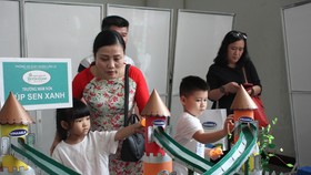 Các em học sinh mầm non xem mô hình đồ chơi làm từ vỏ hộp sữa
