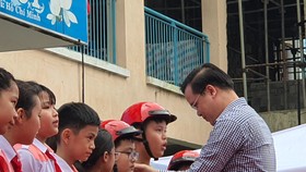Thầy Trần Nguyễn Minh Thành trao tặng mũ bảo hiểm cho các em học sinh lớp 5 có hoàn cảnh gia đình khó khăn