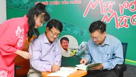 Nhà báo Huỳnh Dũng Nhân ký tặng sách cho độc giả trong buổi ra mắt tác phẩm "Chúng tôi - Một thời mũ rơm, mũ cối"