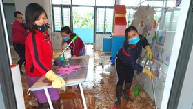 Giáo viên dọn vệ sinh trường lớp sau lũ. Ảnh: DƯƠNG QUANG