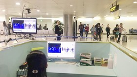 Nhân viên sân bay Tân Sơn Nhất kiểm tra màn hình hiển thị máy quét thân nhiệt đối với hành khách quốc tế đến Việt Nam. Ảnh: TTXVN