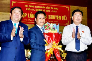 Bí thư Tỉnh ủy Cà Mau Nguyễn Tiến Hải (phải) và Chủ tịch HĐND tỉnh, ông Trần Văn Hiện (trái) tặng hoa chúc mừng tân Chủ tịch UBND tỉnh, ông Lê Quân