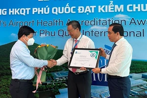 Ông Tống Phước Trường, Bí thư Thành uỷ Phú Quốc (bìa trái) và ông Huỳnh Quang Hưng, Chủ tịch UBND TP Phú Quốc (bìa phải) trao hoa và giấy chứng nhận cho đại diện Cảng HKQT Phú Quốc