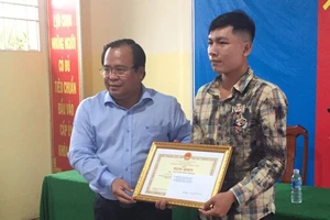 Phó Chủ tịch UBND tỉnh Cà Mau Nguyễn Minh Luân (trái) trao Bằng khen cho anh Nguyễn Hiền Phong