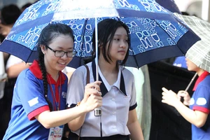Các tình nguyện viên tại TPHCM hỗ trợ thí sinh vào phòng thi trong cơn mưa chiều 23-6 tại Hội đồng thi Trường THPT Marie Curie. Ảnh: HOÀNG HÙNG
