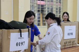 Sinh viên tình nguyện hỗ trợ thí sinh cất đồ đạc cá nhân tại điểm thi Trường THPT Việt Đức, quận Hoàn Kiếm, Hà Nội. Ảnh: QUANG PHÚC 