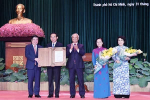 Phó Chủ tịch Quốc hội Uông Chu Lưu trao Nghị quyết của Ủy ban Thường vụ Quốc hội về việc sắp xếp các đơn vị hành chính cấp huyện, cấp xã và thành lập TP Thủ Đức thuộc TPHCM cho lãnh đạo TPHCM. Ảnh: VIỆT DŨNG