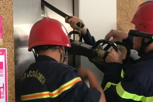 Lực lượng PCCC TPHCM dùng dụng cụ chuyên dụng phá cửa thang máy, đưa 9 nạn nhân mắc kẹt bên trong ra ngoài