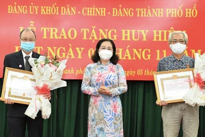 Chủ tịch HĐND TPHCM Nguyễn Thị Lệ trao Huy hiệu 45 năm tuổi Đảng cho đồng chí Ca Lê Thắng và đồng chí Bùi Quang Cảnh. Ảnh: VIỆT DŨNG