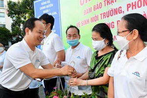 Chủ tịch UBND quận 1 Lê Đức Thanh tặng chậu cây xanh cảm ơn các hộ dân. Ảnh: VIỆT DŨNG 