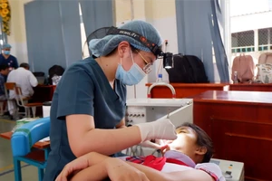 Nhân viên y tế đang thăm khám răng cho học sinh Trường Tiểu học Cần Thạnh (huyện Cần Giờ)