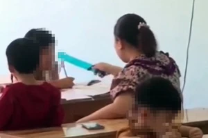 Người phụ nữ dùng thước kẻ đánh học sinh khi đang dạy chữ. Ảnh cắt từ clip