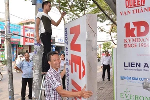  Người dân buôn bán trên đường Nguyễn Thị Thập, quận 7 tự nguyện tháo dỡ bảng quảng cáo lấn chiếm vỉa hè, vào đầu tháng 3-2017. Ảnh: Việt Dũng