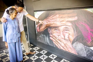 ​ Réhahn và bà Xong bên tác phẩm “Nụ cười ẩn giấu” tại buổi ra mắt phòng ảnh nghệ thuật ở TPHCM