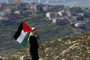 Một người đàn ông Palestine vẫy cờ Palestine trong cuộc biểu tình phản đối các khu định cư của Israel tại thành phố Nablus, Bờ Tây, hôm 26-2-2021. Ảnh: EPA