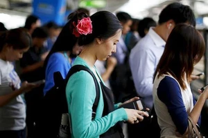 Sử dụng điện thoại di động tại một ga xe lửa ở Bangkok, Thái Lan. Ảnh: REUTERS