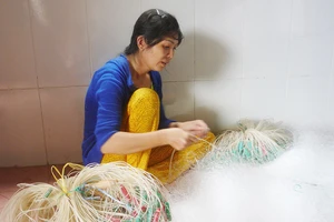 Chị Nguyễn Thị Bé Vinh dù bệnh tật vẫn gắng đan lưới kiếm tiền nuôi 2 con