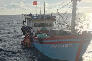 Các nhân viên tàu SAR 412 đưa xuồng cao su tiếp cận tàu cá và chuyển ngư dân Lê Thanh Hải sang tàu SAR 412 đưa về đất liền cấp cứu