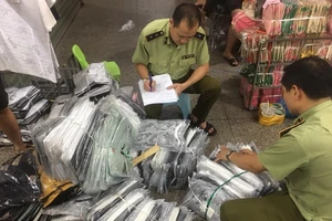 Cán bộ QLTT kiểm kê các lô hàng thời trang nhái, lậu trong chợ Ninh Hiệp hôm 4-6