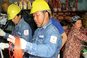 Nhân viên điện lực sửa chữa, thay thế thiết bị điện hư hỏng cho hộ gia đình nghèo tại quận 6 Ảnh: Nguyễn Hưng