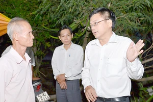 Phó Chủ tịch UBND huyện Bình Chánh Nguyễn Văn Tài (bìa phải) trực tiếp đến nhà ông Võ Văn Kim vào buổi tối để vận động việc giải phóng mặt bằng xây dựng đường cao tốc Bến Lức - Long Thành Ảnh: VIỆT DŨNG