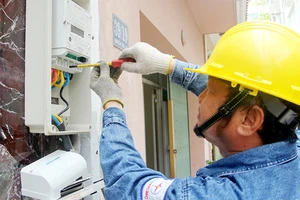 Công nhân điện lực đang thay điện kế điện tử cho khách hàng