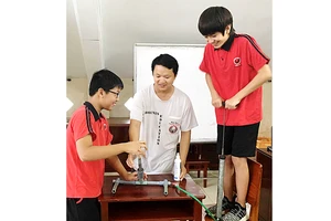 Thầy Nguyễn Tường Vũ (giữa) và học sinh tại phòng thí nghiệm Vật lý của Trường quốc tế Phượng Hoàng