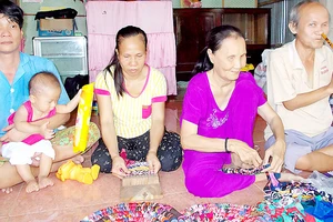 Vợ chồng chị Lợi (bên trái) và 2 hội viên khiếm thị đang học nghề đan thảm chùi chân tại nhà