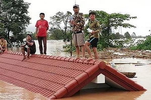 Người dân đứng trên nóc nhà chờ giải cứu khi nước lũ dâng cao do vỡ đập