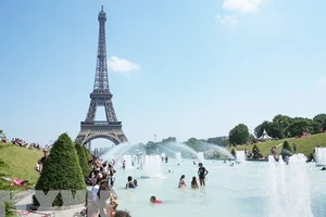 Người dân tránh nắng nóng bên vòi phun nước ở Paris, Pháp. Ảnh: TTXVN