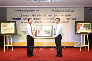 Bộ trưởng Bộ Thông tin và Truyền thông Nguyễn Mạnh Hùng (phải) tặng bức tem cho Trưởng Ban Tuyên giáo Trung ương Võ Văn Thưởng. Ảnh: TTXVN