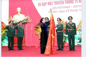 Chủ tịch Quốc hội Nguyễn Thị Kim Ngân gắn Huy hiệu Anh hùng LLVT lên lá cờ truyền thống của Tổng cục II. Ảnh: TTXVN