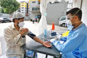 Nhân viên y tế lấy mẫu xét nghiệm COVID-19 tại khu nhà tập thể Toh Guan ở Singapore. Ảnh: THX/TTXVN
