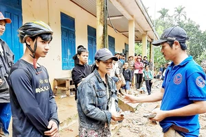 Thầy giáo Nguyễn Trần Vỹ (bìa phải) trao tặng tiền hỗ trợ bà con xã Trà Leng, Quảng Nam, bị bão số 9 làm hư hại tài sản