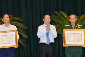 Ủy viên Trung ương Đảng, Phó Bí thư Thường trực Thành ủy TPHCM Tất Thành Cang trao tặng và chúc mừng các đồng chí nhận Huân chương Độc lập hạng Ba. Ảnh: VIỆT DŨNG