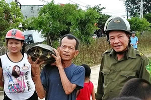 Ông Thể và đại diện chính quyền địa phương cùng người dân mang con rùa đi thả về lại môi trường tự nhiên