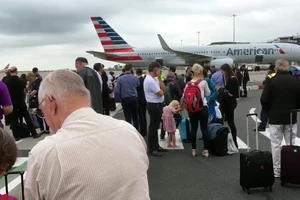 Hành khách tập trung trên đường băng sau khi được sơ tán khỏi máy bay ở sân bay Manchester, Anh, ngày 5-7-2017. Ảnh: AP