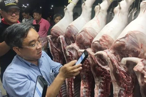 Lãnh đạo Sở Công thương TPHCM kiểm tra quét mã vạch truy xuất nguồn gốc thịt heo tại chợ đầu mối sáng 31-7-2017. Ảnh: THANH HẢI 