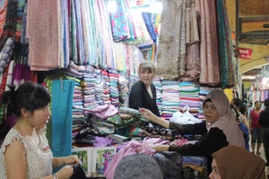Khách hàng tìm mua khăn quàng cổ tại một sạp ở chợ Bến Thành ngày 26-10