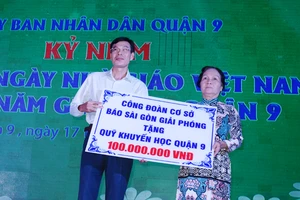 Ông Phạm Trường, Phó Tổng Biên tập Báo Sài Gòn Giải Phóng, trao bảng tượng trưng ủng hộ Quỹ Khuyến học Quận 9 (TPHCM) 100 triệu đồng. Ảnh: TRỌNG NGHI