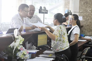 Nhân viên Cục Thuế TPHCM hướng dẫn làm hồ sơ khai thuế Ảnh: CAO THĂNG